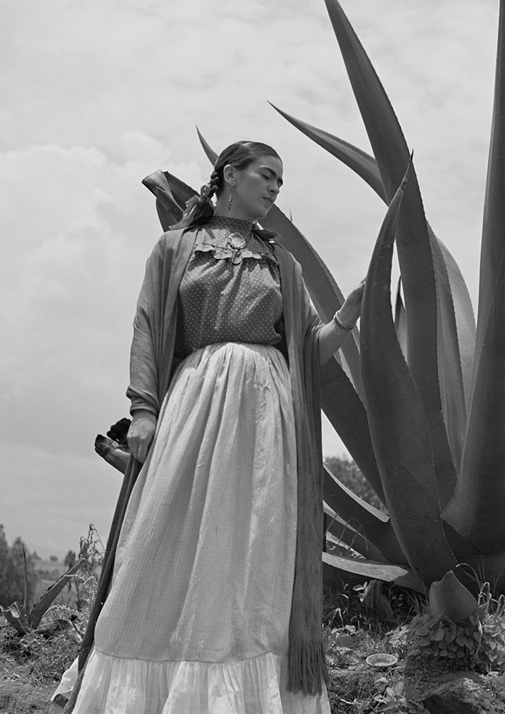 Frida Kahlo standing next to an agave plant