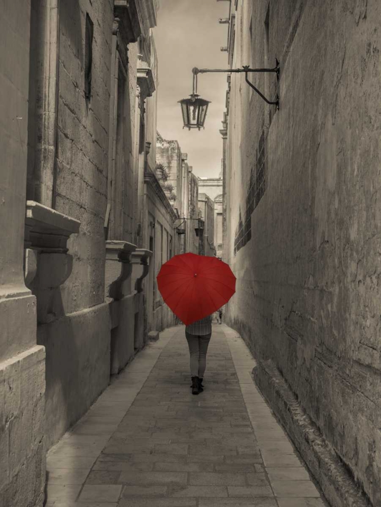 Tourist with heart shaped umbrella walking through narrow street of Mdina, Malta