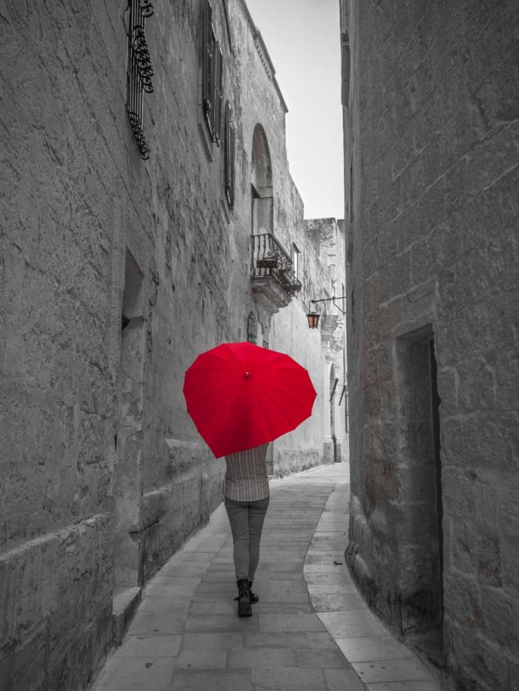Tourist with heart shaped umbrella walking through narrow street of Mdina, Malta