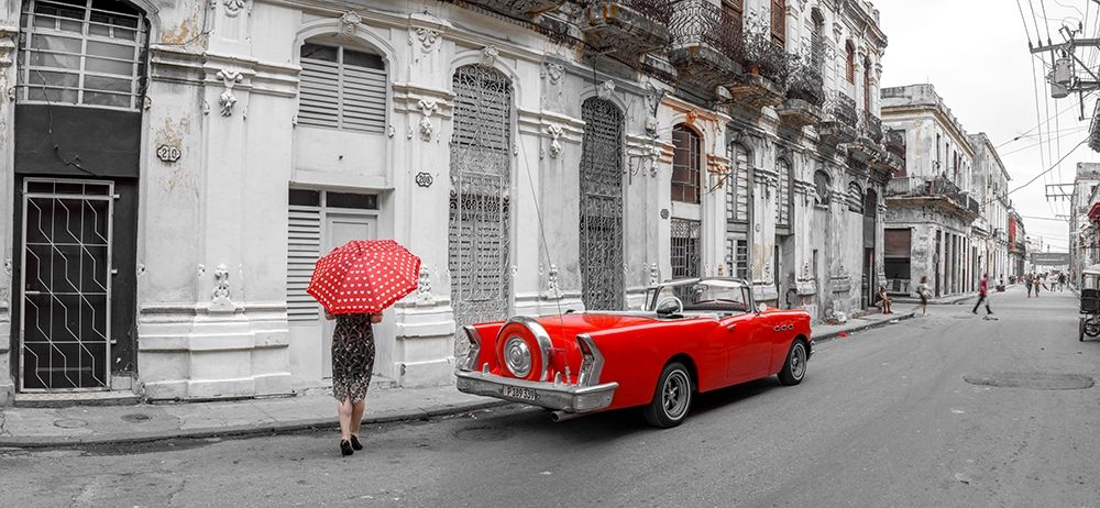 Woman with red umbrella by a vintage car on the street of Havana-Cuba