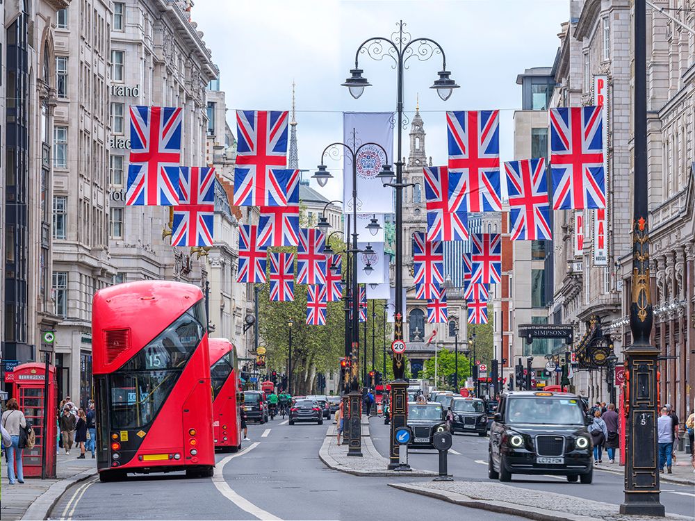 Double decker buses and taxis on street of London with British flags