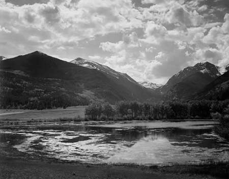 Lake and trees in foreground, mountains and clouds in background, in Rocky Mountain National Park, C